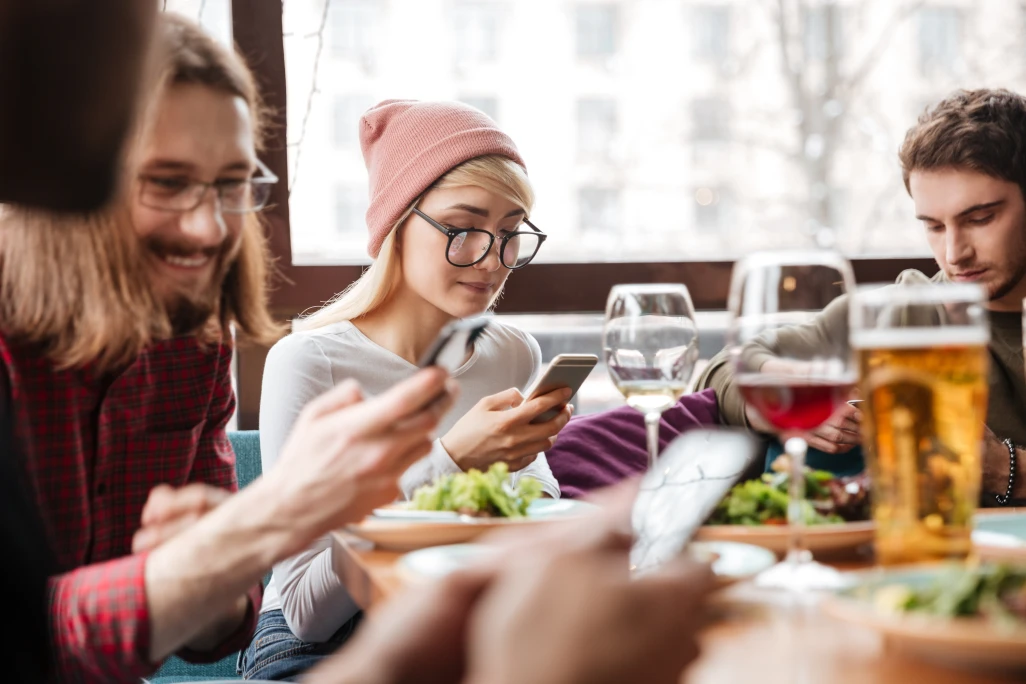 Acquire new customers for restaurants - people at a table using their phones